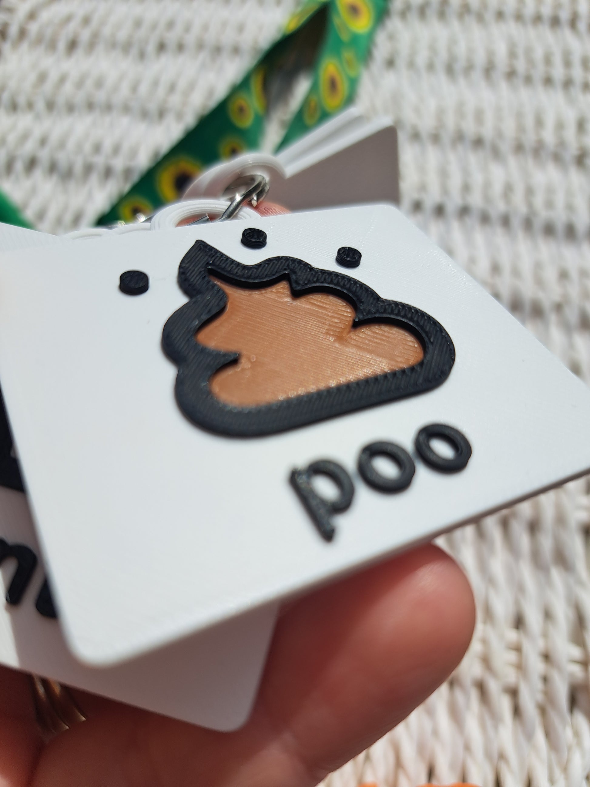 Close-up of the ‘poo’ tag from the toilet communication set, showing raised text and symbol.