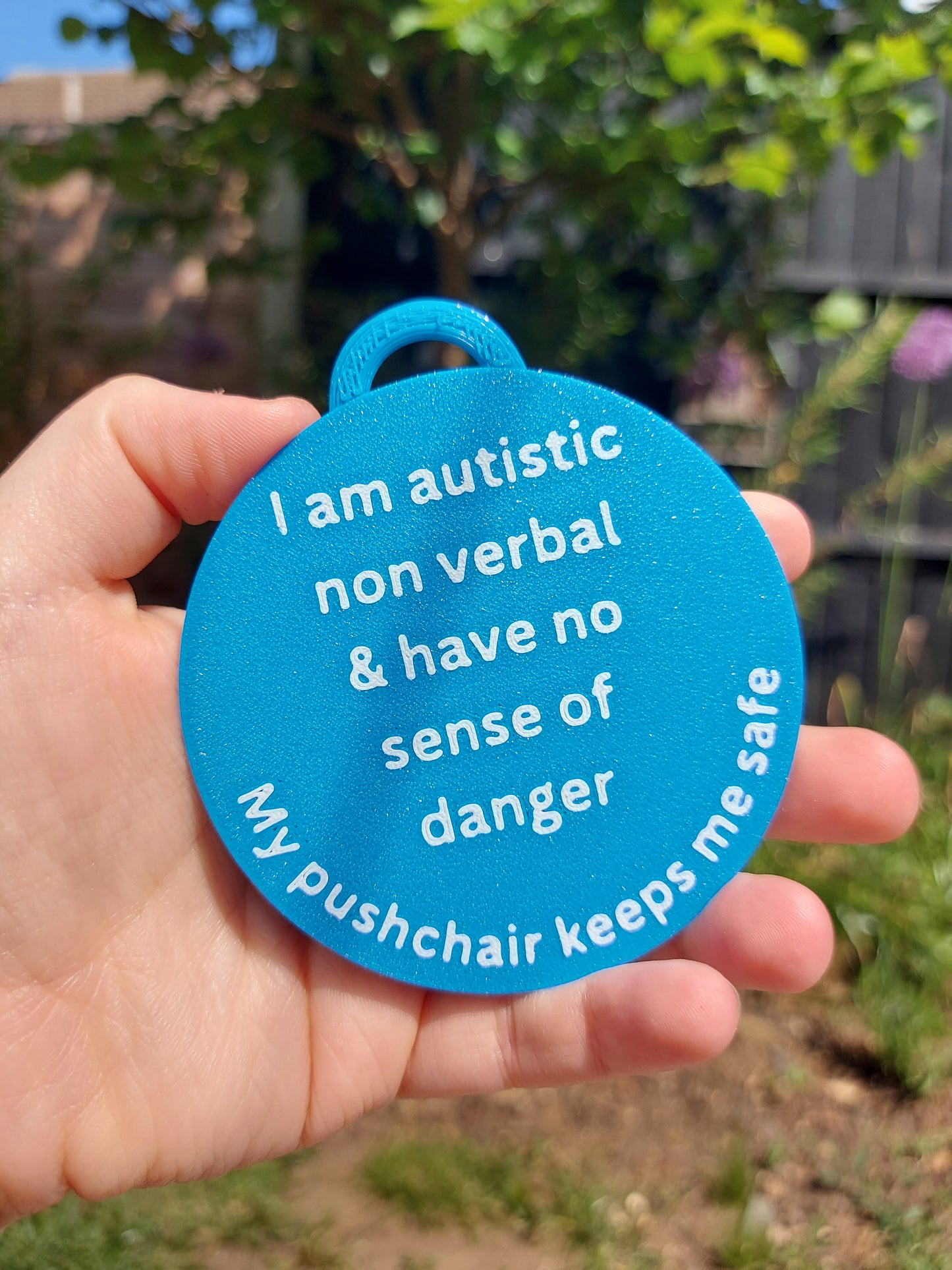 Blue identity tag with text held in a hand outdoors