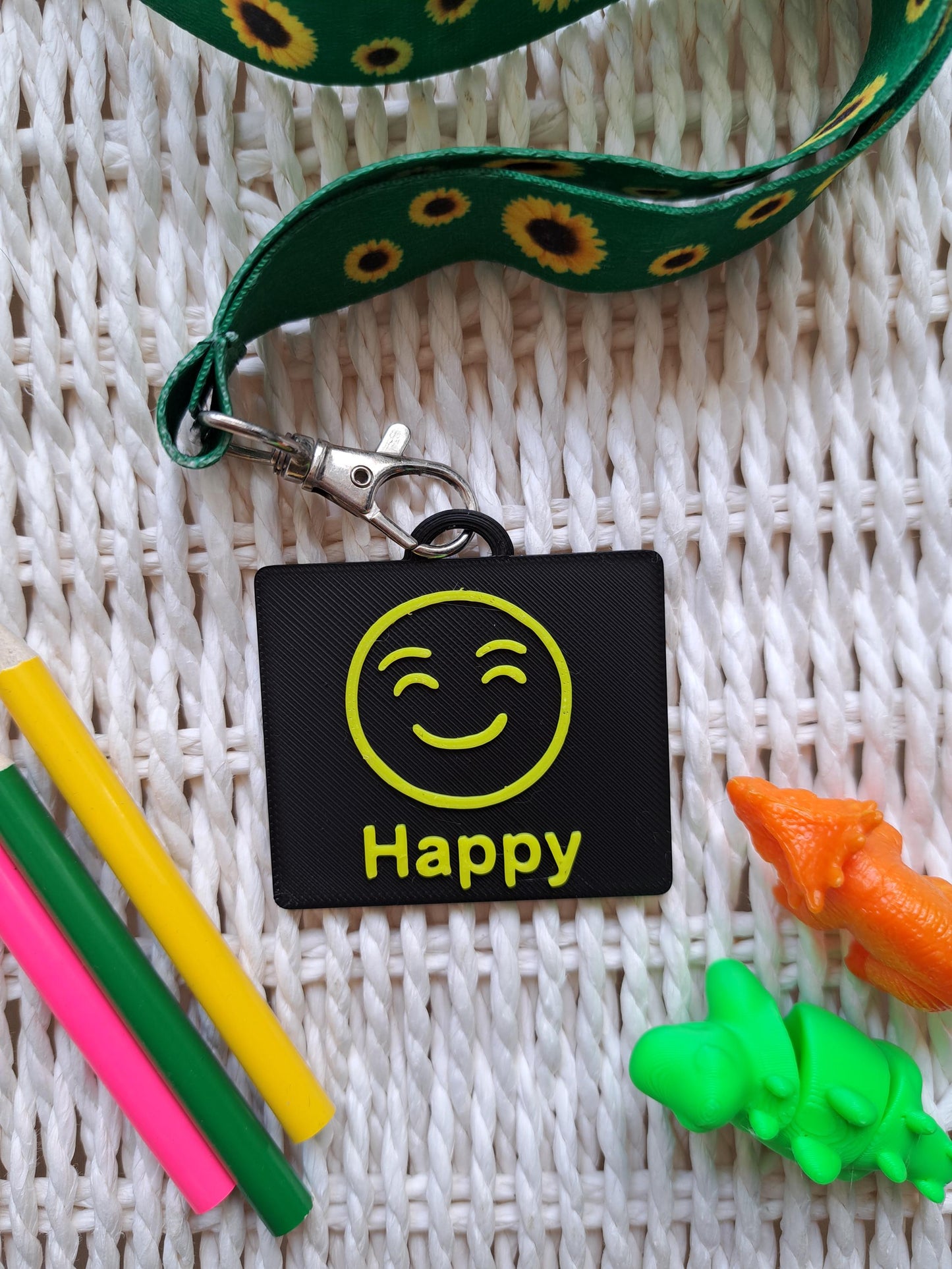 A black-colored 3D-printed communication tag with a raised yellow "happy" face and the word "happy" below it. This visual aid tag is designed to support nonverbal communication, autism-friendly tools, and AAC needs.