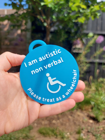 Blue badge with text and wheelchair symbol held in hand outdoors