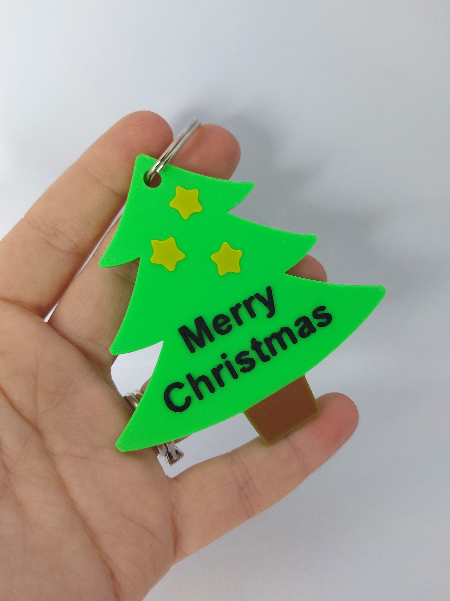 Green Christmas tree-shaped keychain with 'Merry Christmas' text on a white background