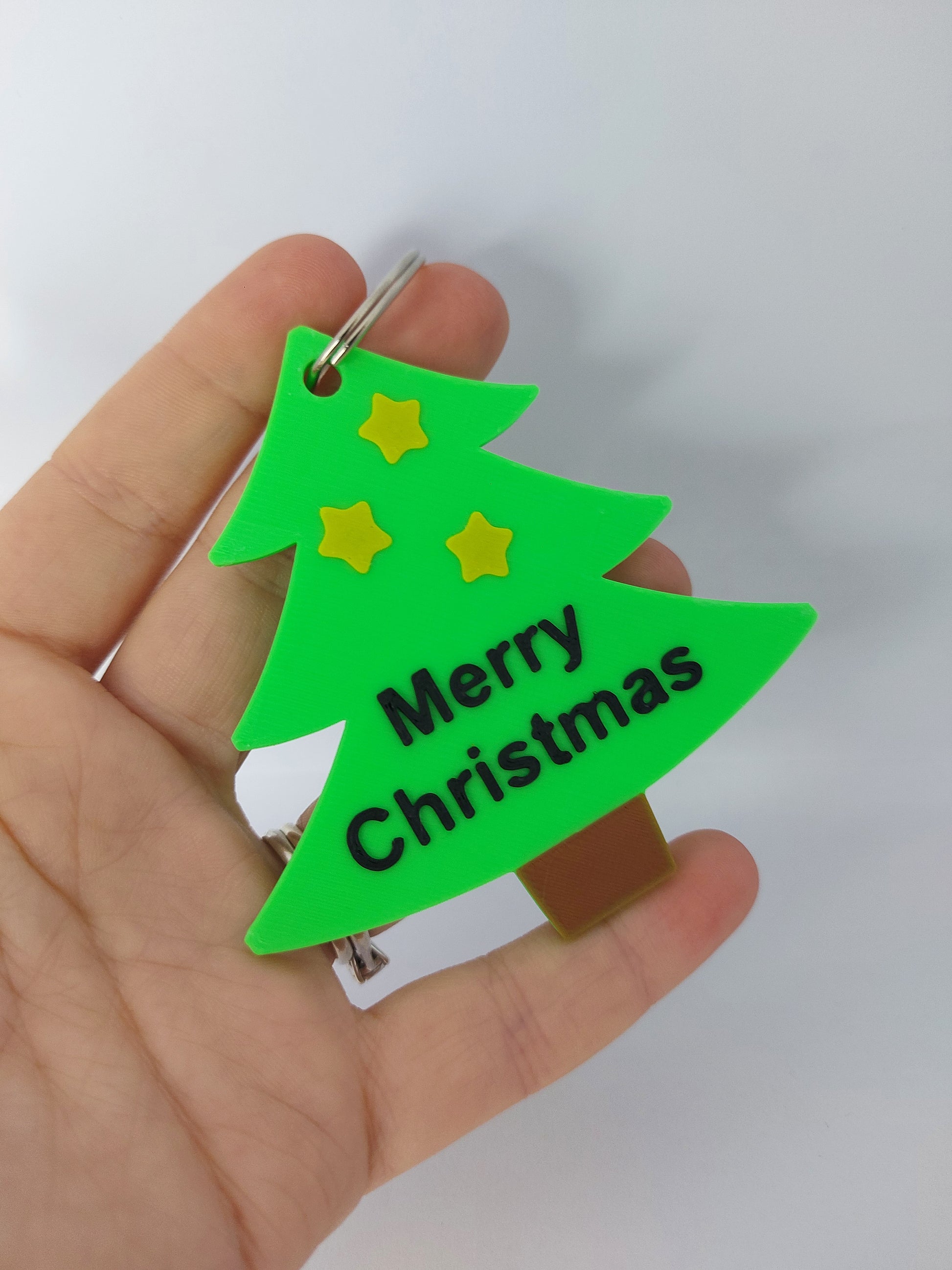 Green Christmas tree-shaped keychain with 'Merry Christmas' text on a white background